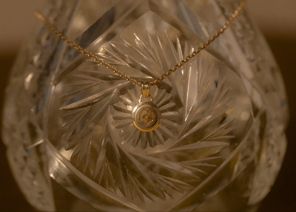 Decorative glass object with a gold necklace draped over it